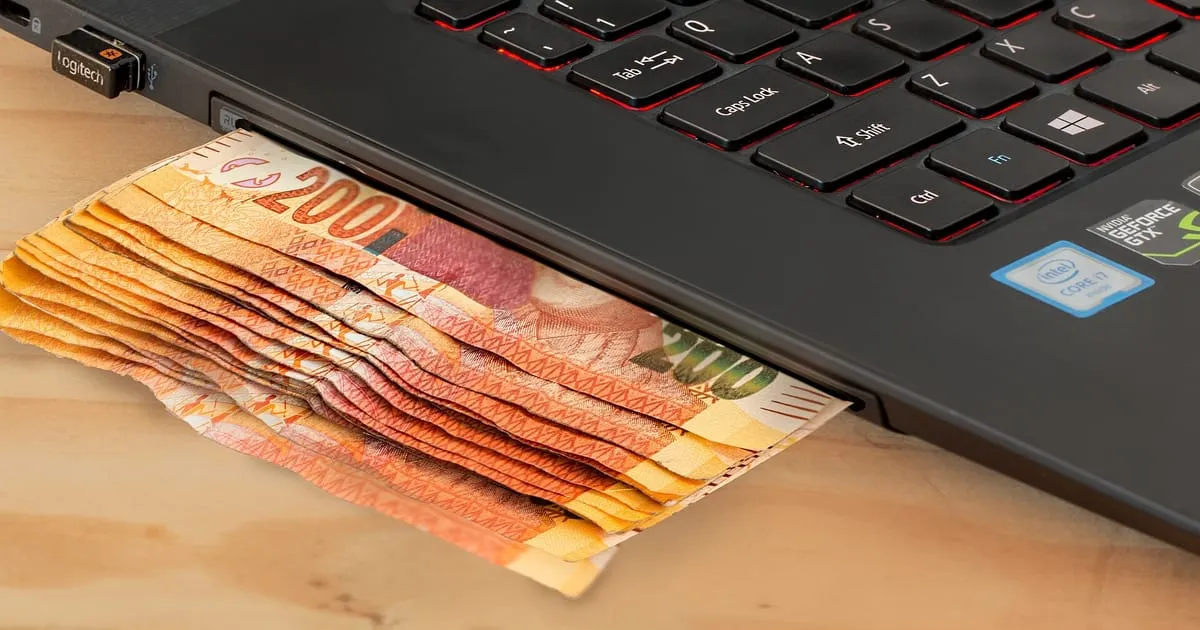 Billetes saliendo de una computadora portátil