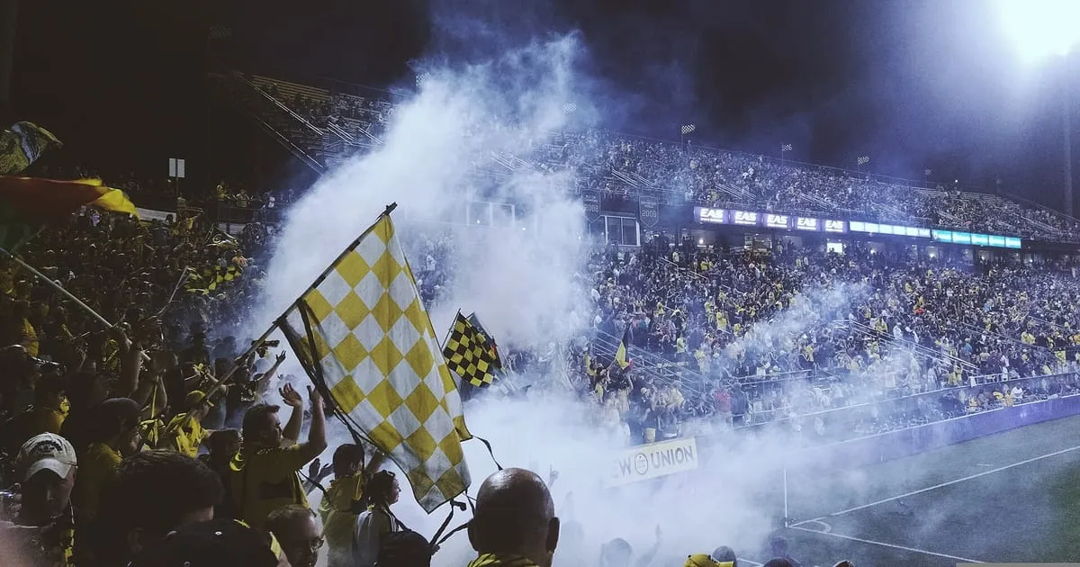 Aficionados con banderas y humo en la tribuna de un estadio